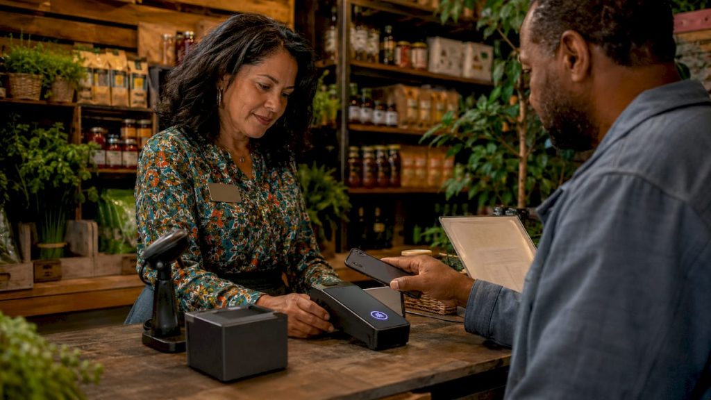 Retail cashier accepting pay by phone transaction for secure payments.